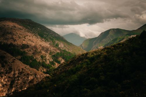 Free Moody view of mountains with dramatic clouds overhead in a lush landscape. Stock Photo