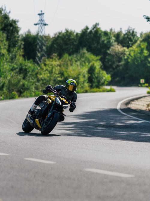 Free Motorcyclist leaning into a turn on a forest road, capturing speed and thrill. Stock Photo