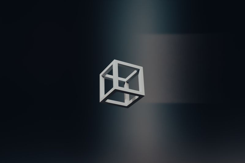 A white open-frame cube suspended in a softly lit dark room — photo by Steve A Johnson on Pexels