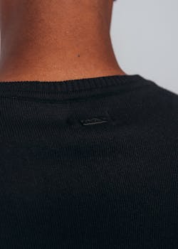 A detailed view of the back of a black sweater, highlighting the texture and tag.