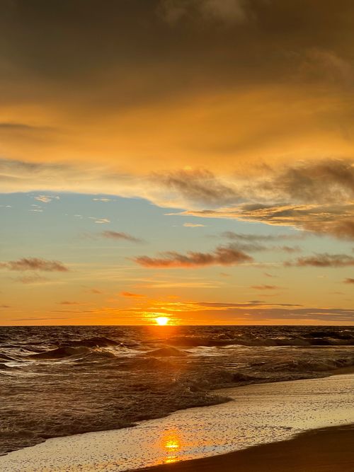 Free Beautiful sunset over a Liberian beach with warm sky tones and ocean waves. Stock Photo