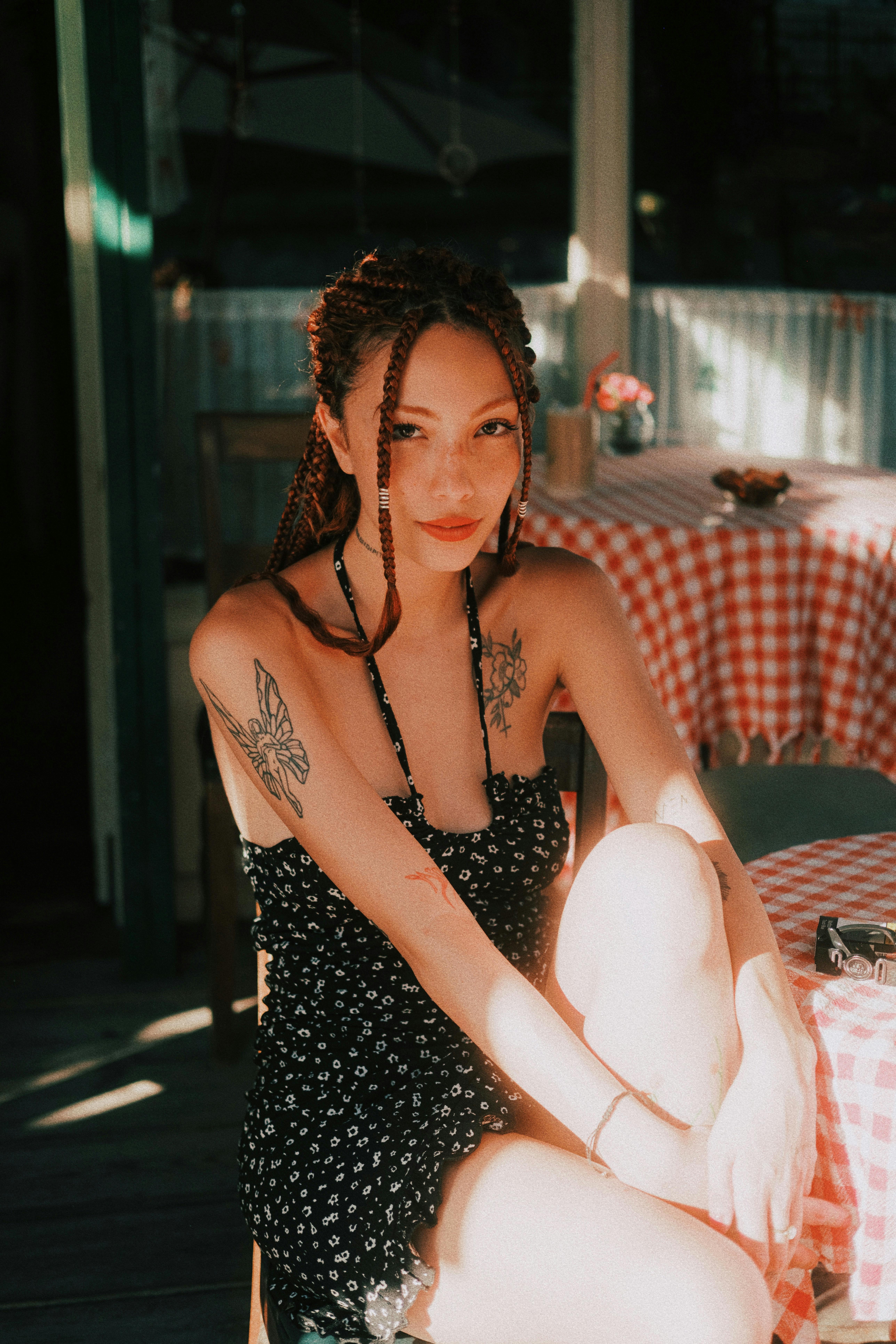 stylish woman with tattoos in sunlit cafe