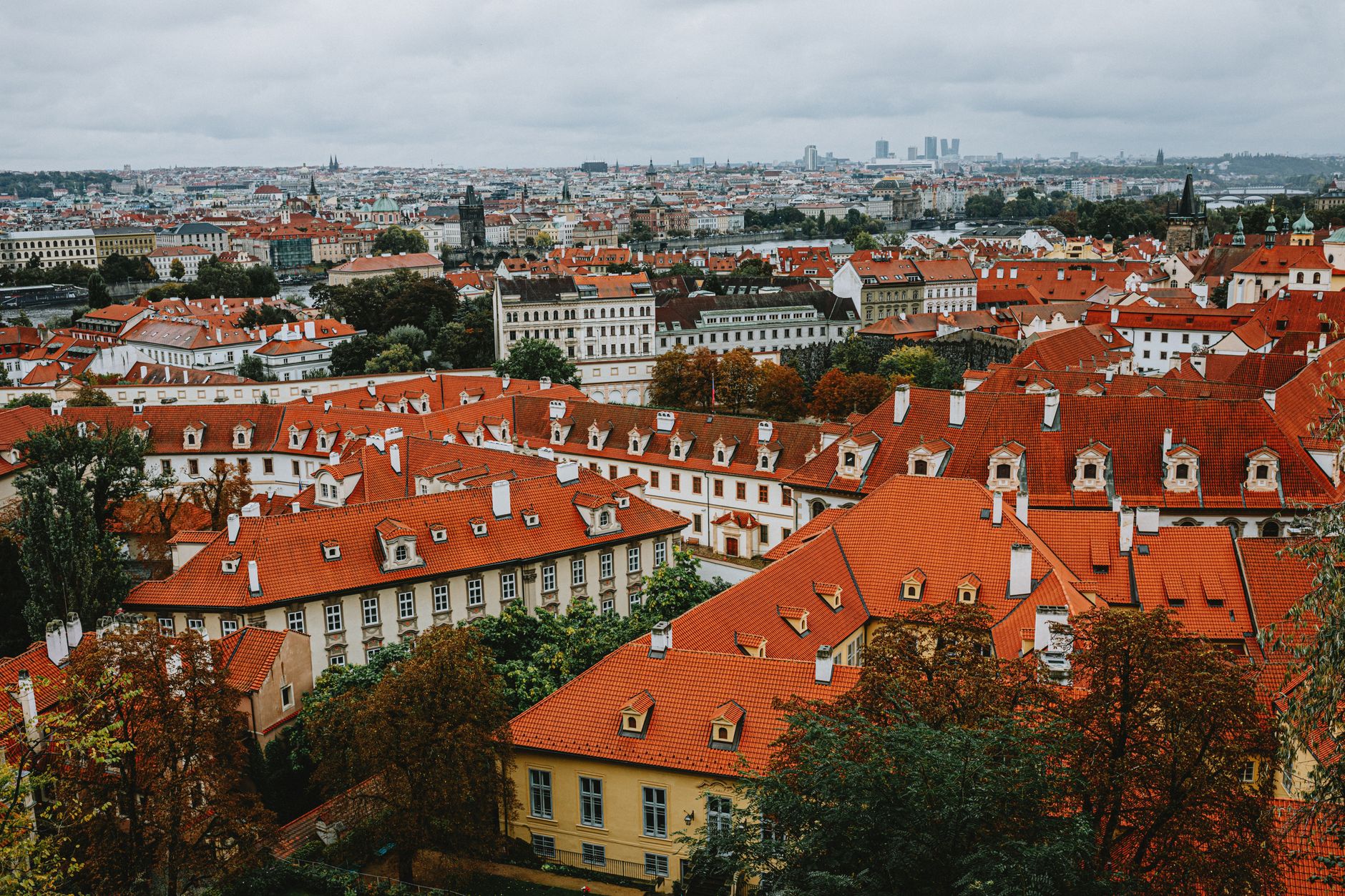 Explore the charming red rooftops of Prague's historic district from an aerial perspective on a cloudy day.