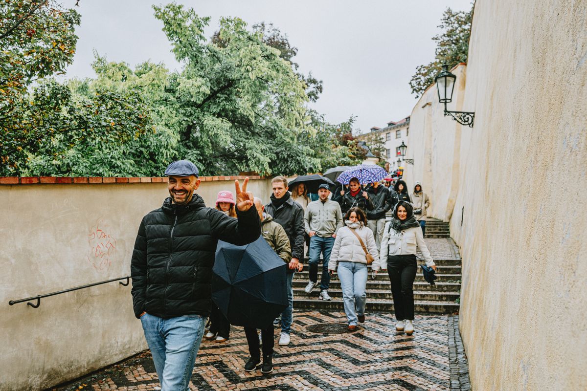 A guide leads a small group of walkers with umbrellas up a cobbled old-town lane — Helena Jankovičová Kováčová on Pexels