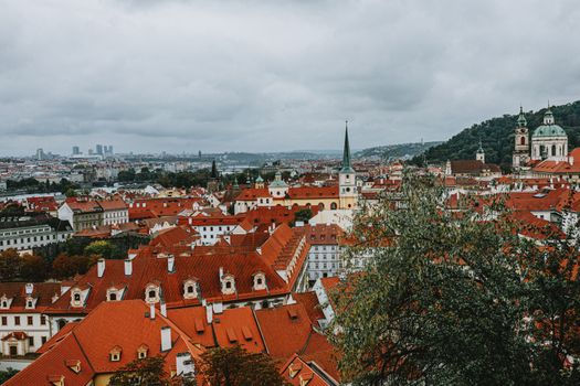 Breathtaking aerial view of Prague with iconic red rooftops and historic architecture under a cloudy sky.
