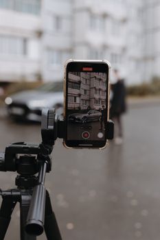 Smartphone on tripod capturing urban street with blurred background.