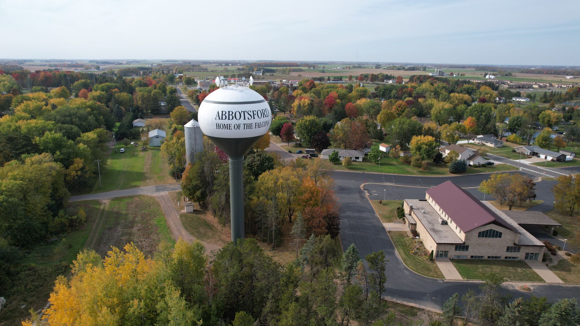 Scenic aerial view of Abbotsford, Wisconsin with fall foliage and a water tower.