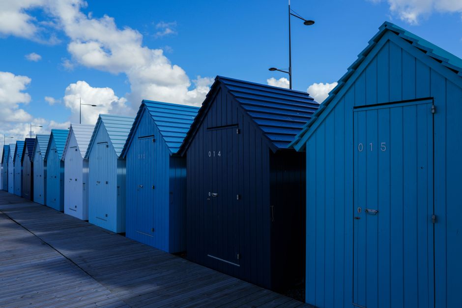 Row of colorful beach huts against a vibrant blue sky. Perfect for travel and architecture themes.
