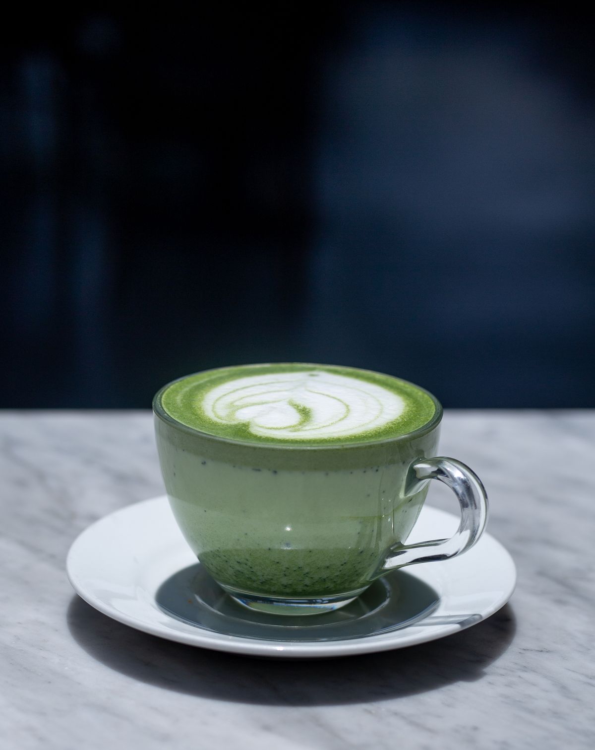 Elegant matcha latte in glass cup on marble table