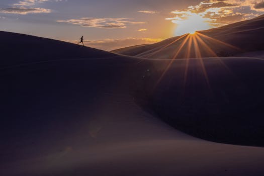 Stunning silhouette of a person running on sand dunes at sunrise in Colorado.