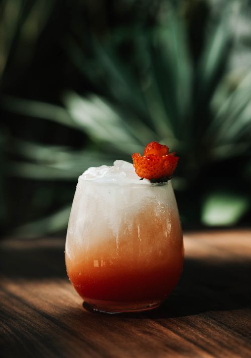 Free Chilled tropical cocktail in a glass with strawberry garnish, set against lush greenery. Stock Photo