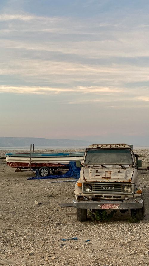 Free Old truck and boat decaying in the serene desert setting of Mirbat, Oman. Stock Photo