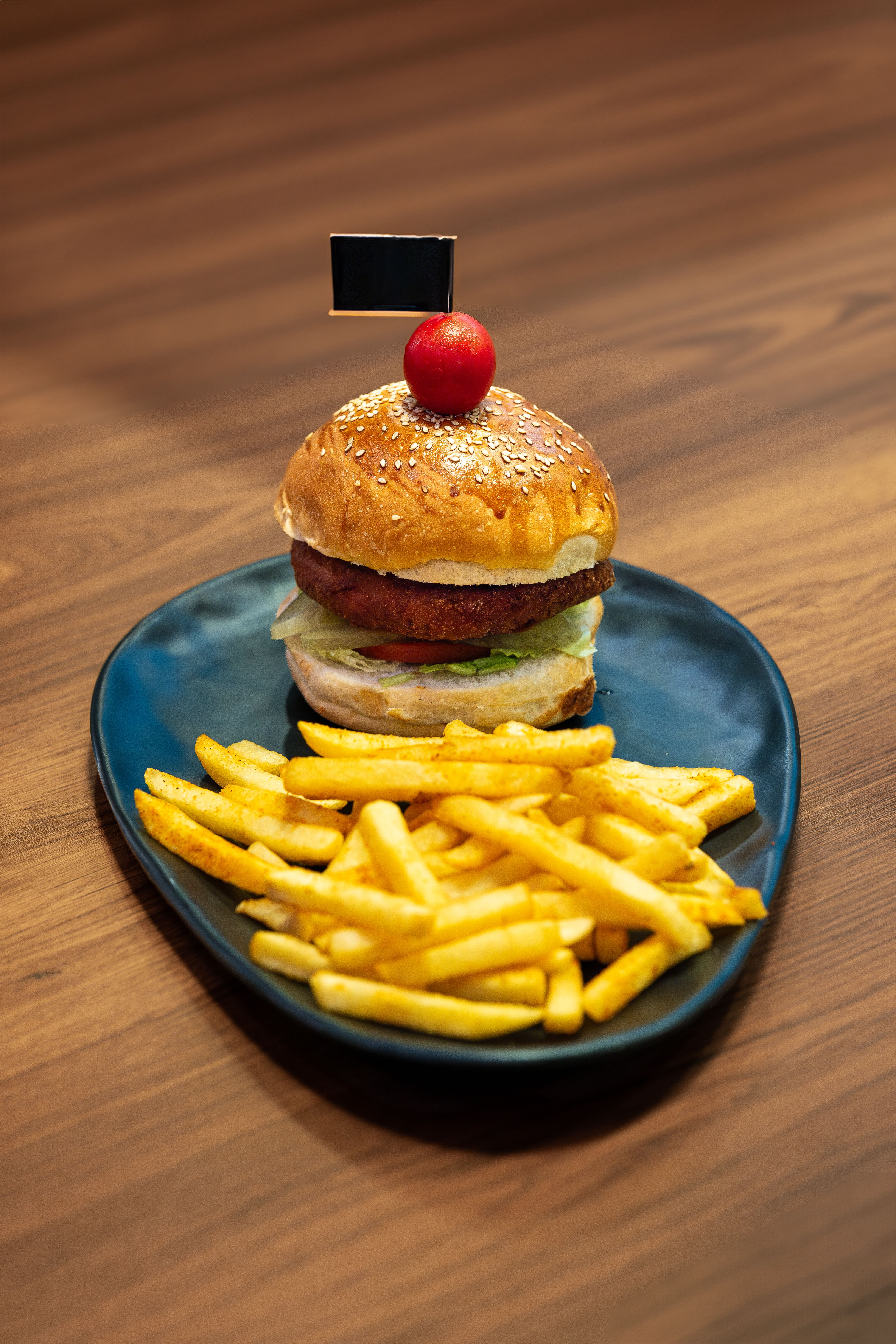 Appetizing burger with fries served on a stylish blue plate.