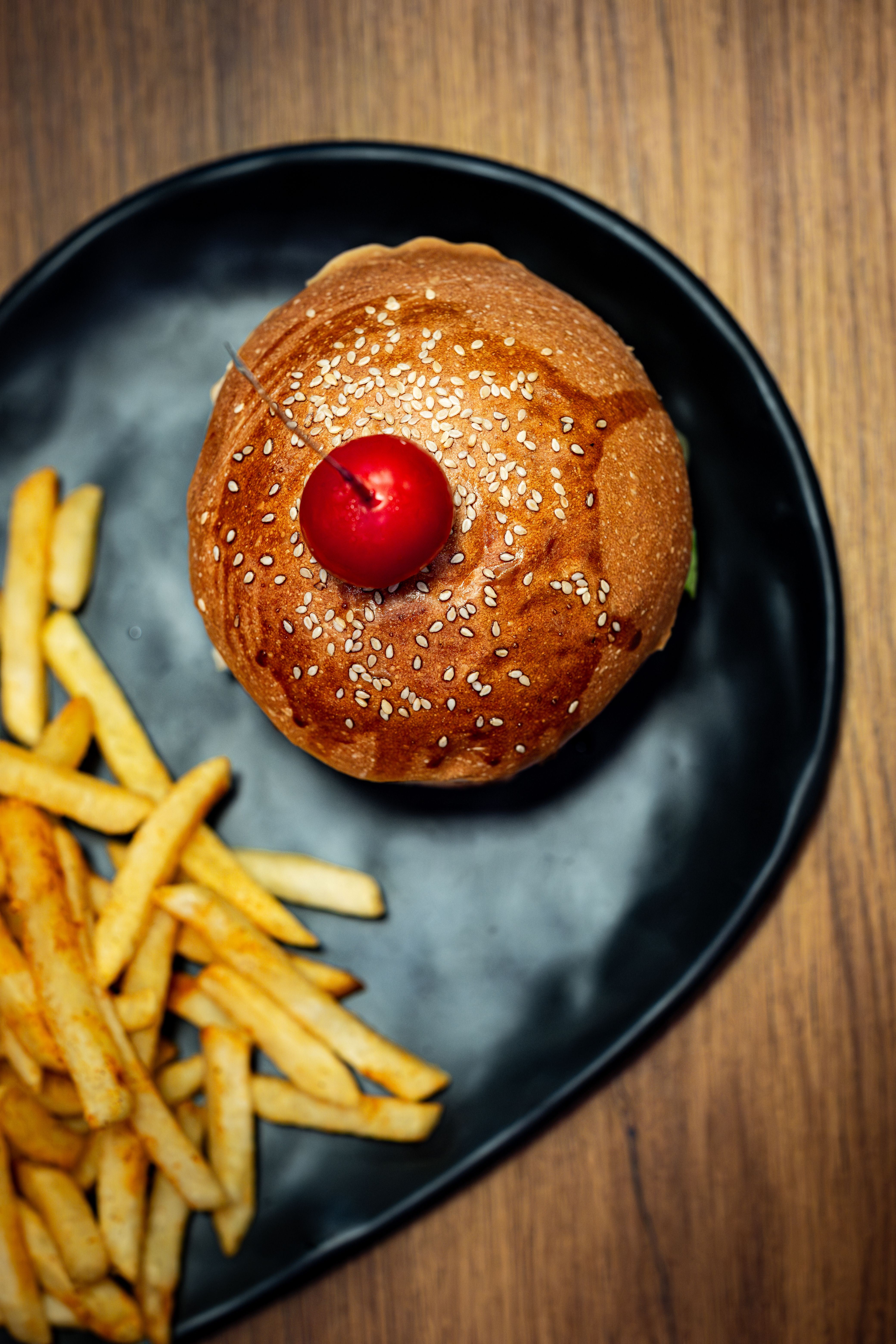Top view of a burger with a cherry on top served with fries in İstanbul.