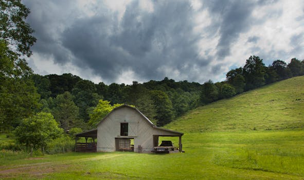 A picturesque barn under dramatic clouds in a serene countryside setting.