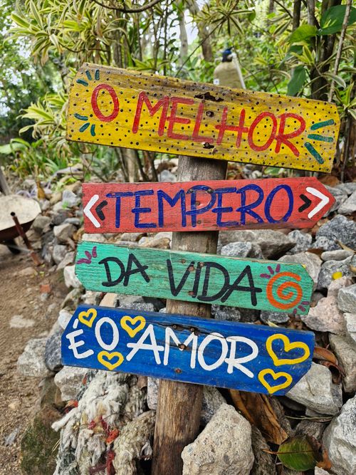 Free Bright, hand-painted sign offering an inspiring message set among garden rocks and plants. Stock Photo
