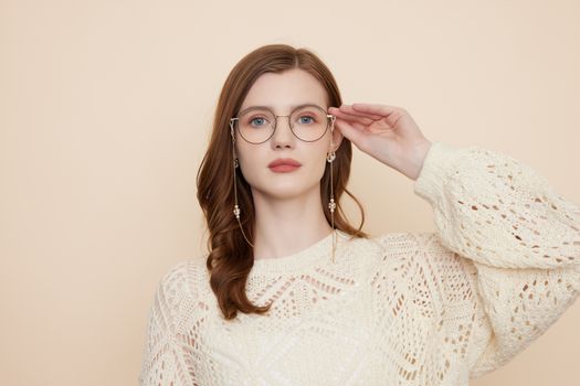 Portrait of a woman in glasses with beige background, embracing fashion style.