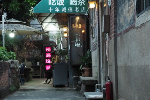 An inviting alley cafe with illuminated signs in an Asian urban setting during twilight.