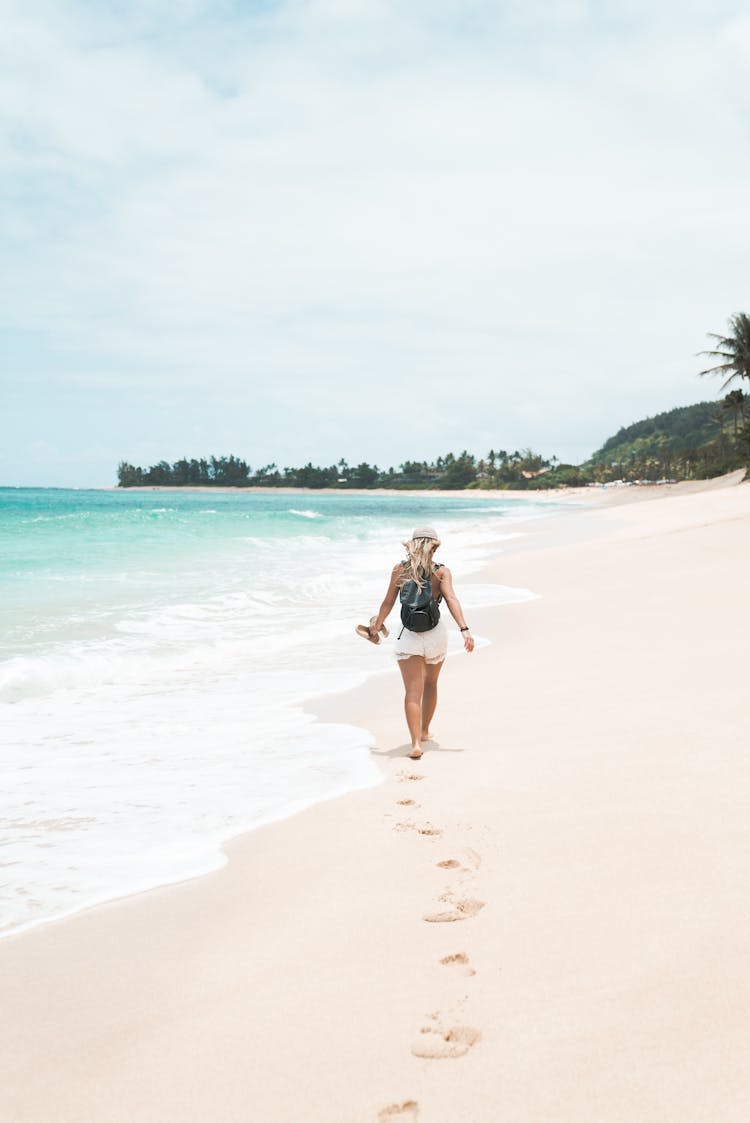 Back View Photo Of Woman Walking Alone On The Beach