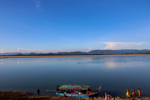 Free A calming river scene in India with distant mountains and a colorful boat. Stock Photo