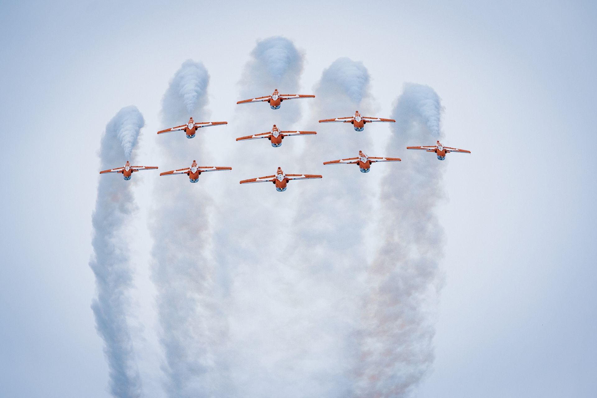 A stunning display of synchronized aerobatic flying by a formation of planes releasing smoke trails.