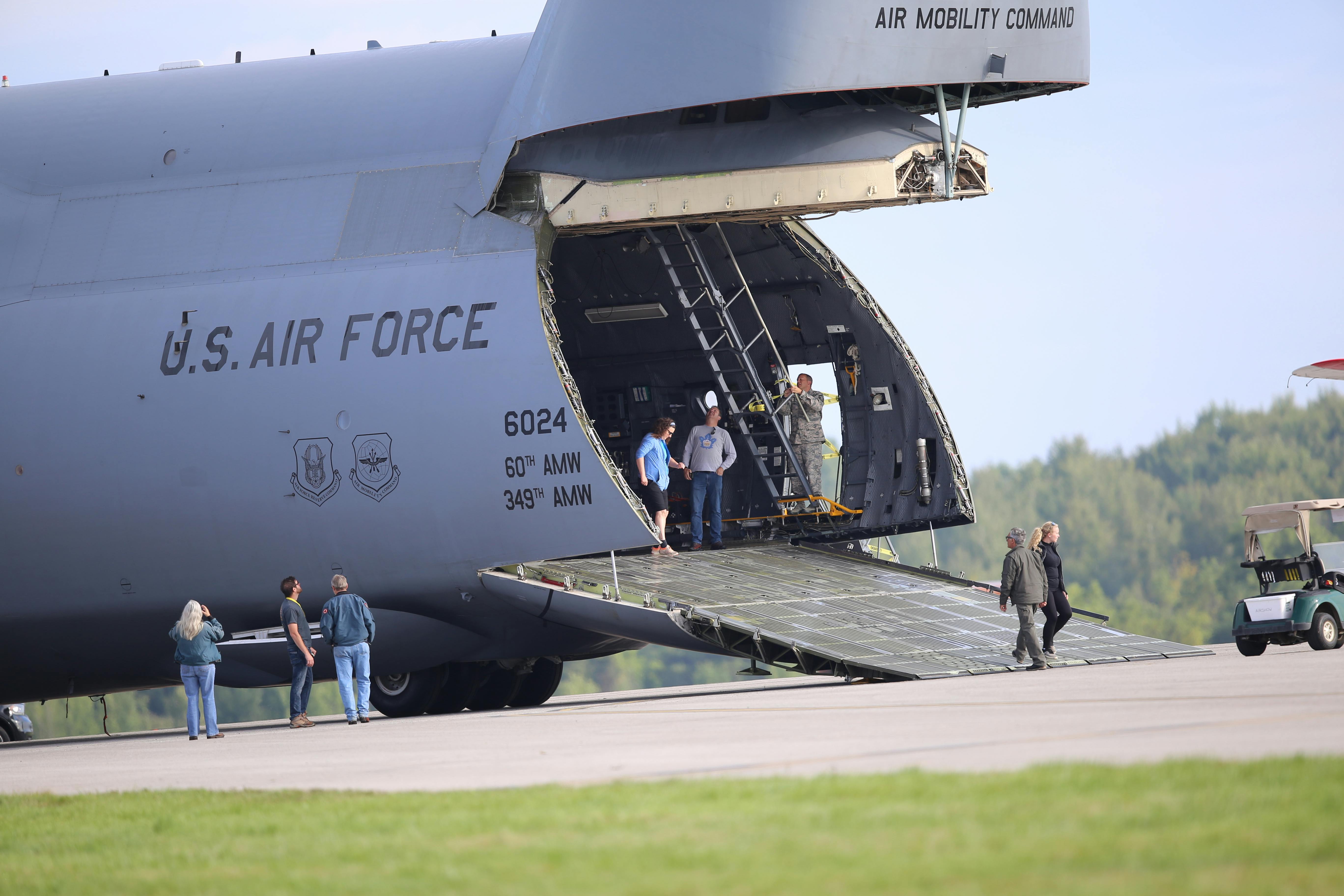 U.S. Air Force cargo plane with open ramp and personnel preparing for loading at the airfield.