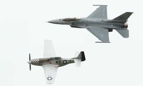 Free Dynamic aerial display featuring F-16 and P-51 Mustang fighter jets in flight. Stock Photo