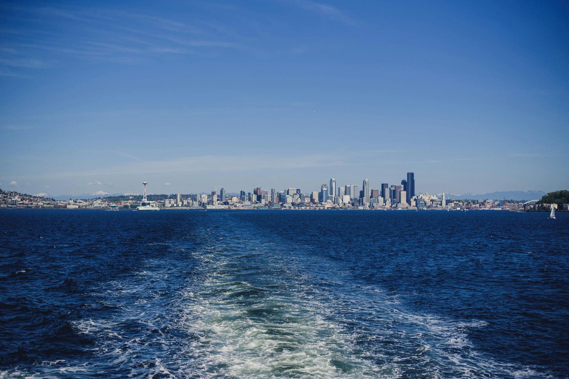 View of Seattle skyline across Puget Sound from a ferry on a sunny day.