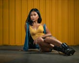 自信的女人倚坐在充满活力的黄色墙壁前，展现都市时尚