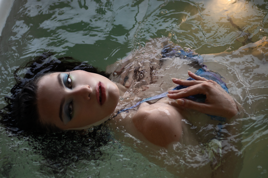 A woman floating in a calm and serene body of water, exuding elegance and tranquility.