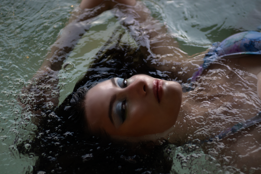 Serene portrait of a woman floating in water with bubbles.