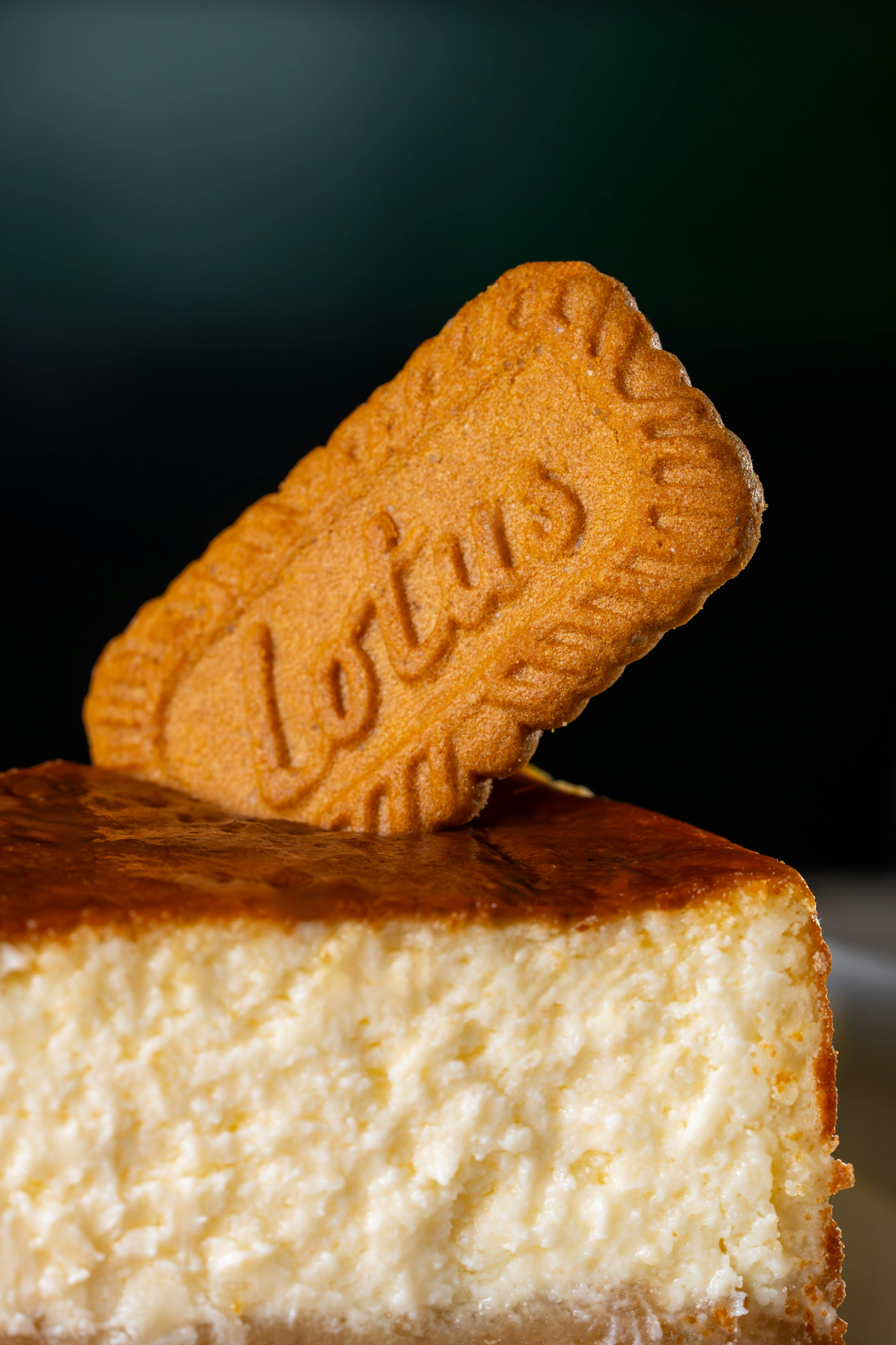 Close-up of a cheesecake slice garnished with a Lotus biscuit.