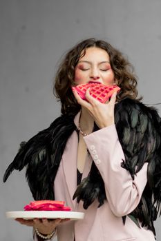 Stylish woman with black feather jacket savoring a pink waffle.