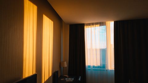 A contemporary hotel room draped in warm morning light casting shadows on the wall.