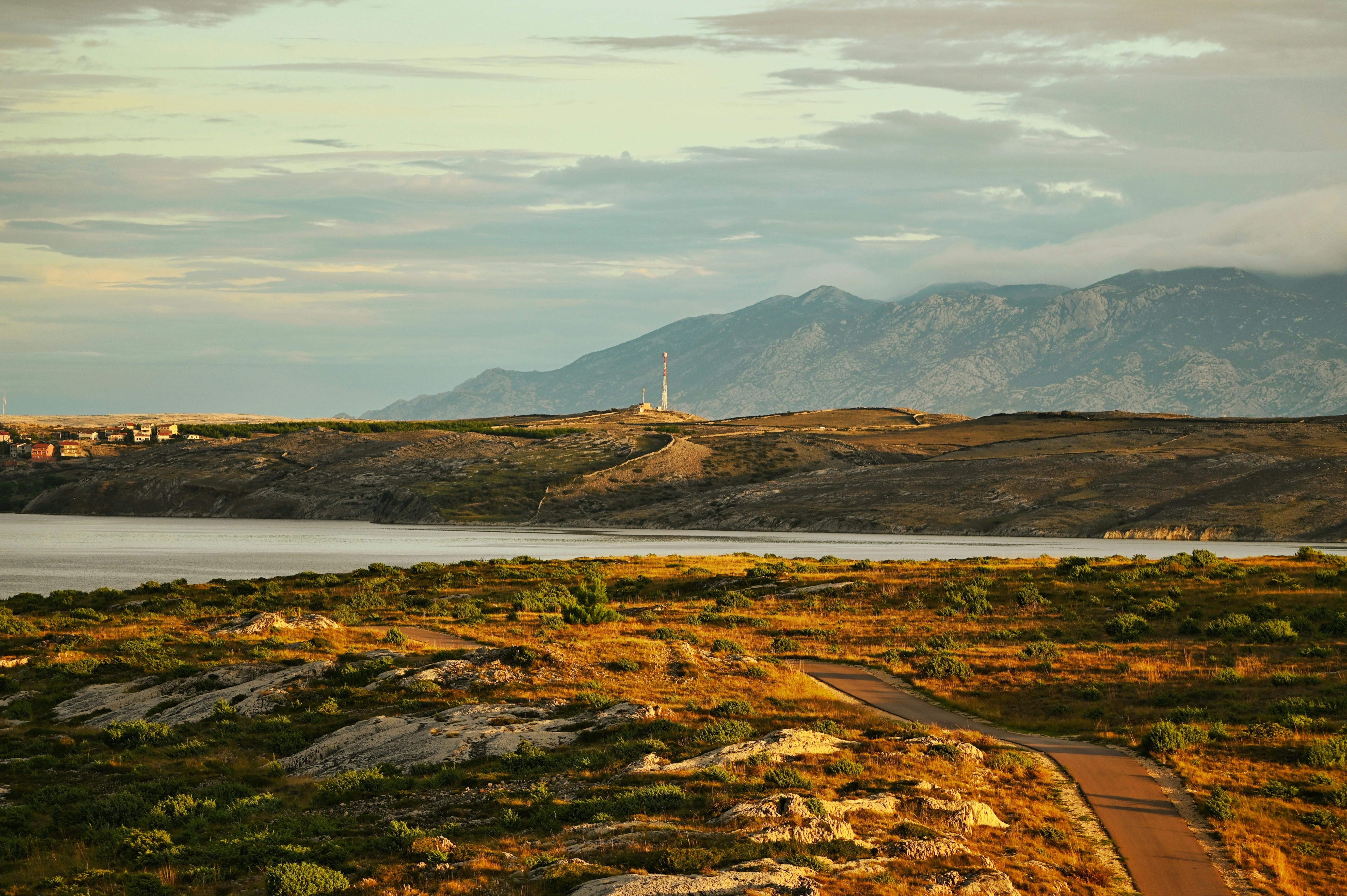 Breathtaking Croatian landscape with mountains, roads, and meadows at daytime.