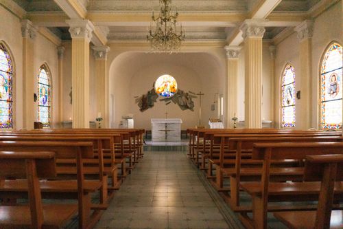 Free Peaceful church interior featuring elegant stained glass windows and wooden pews. Stock Photo
