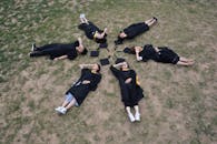 Graduates Lying in Circle on Grass for Celebration