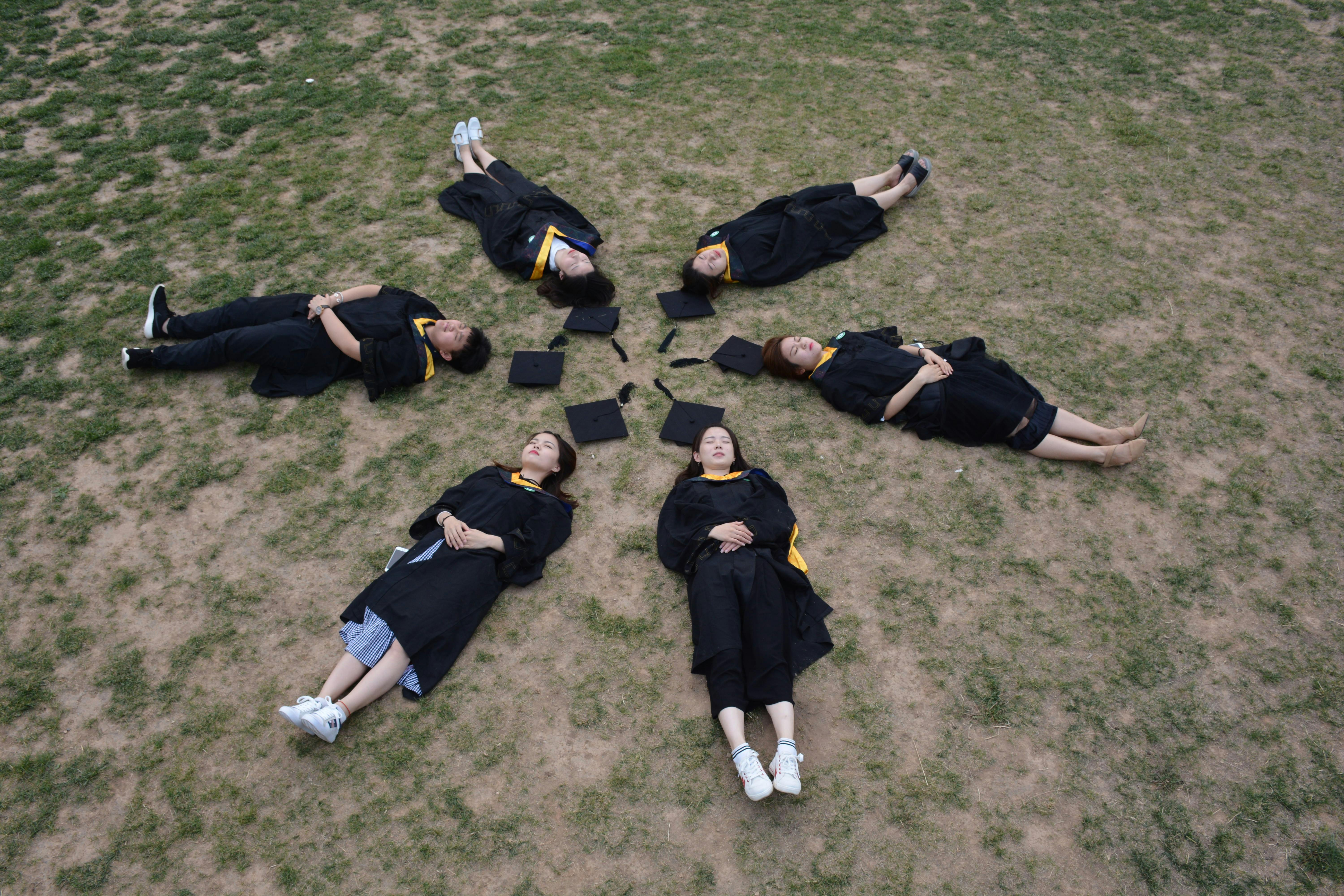 aerial view of graduates lying on grass in circle