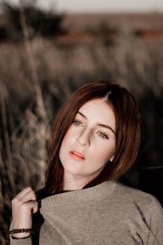 这幅肖像画描绘了一位棕色头发的女子，她在户外的自然光线下，目光移向别处，画面宁静