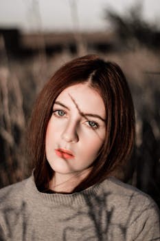 这幅迷人的户外肖像描绘了一位年轻女子，自然光线营造出戏剧性的阴影