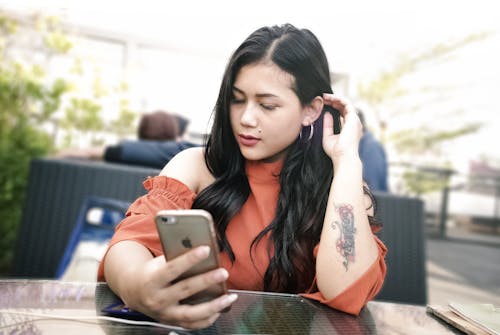 Selektives Fokusfoto Der Frau, Die Smartphone Beim Sitzen Am Tisch Verwendet