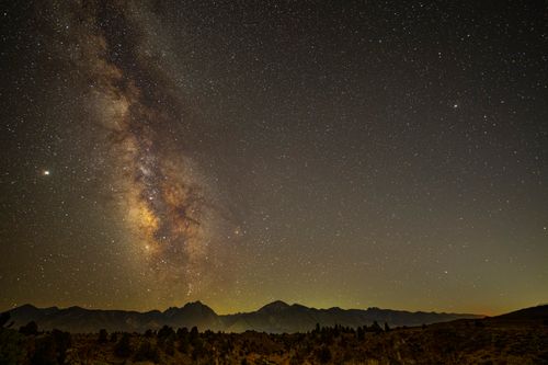 Free A stunning view of the Milky Way galaxy over a mountainous landscape at night. Stock Photo