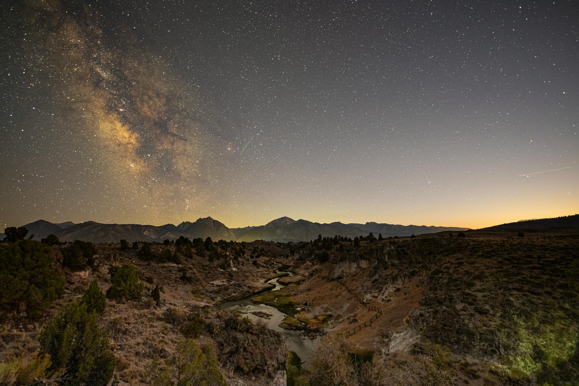 Dramatic Milky Way galaxy over serene mountain landscape at night.