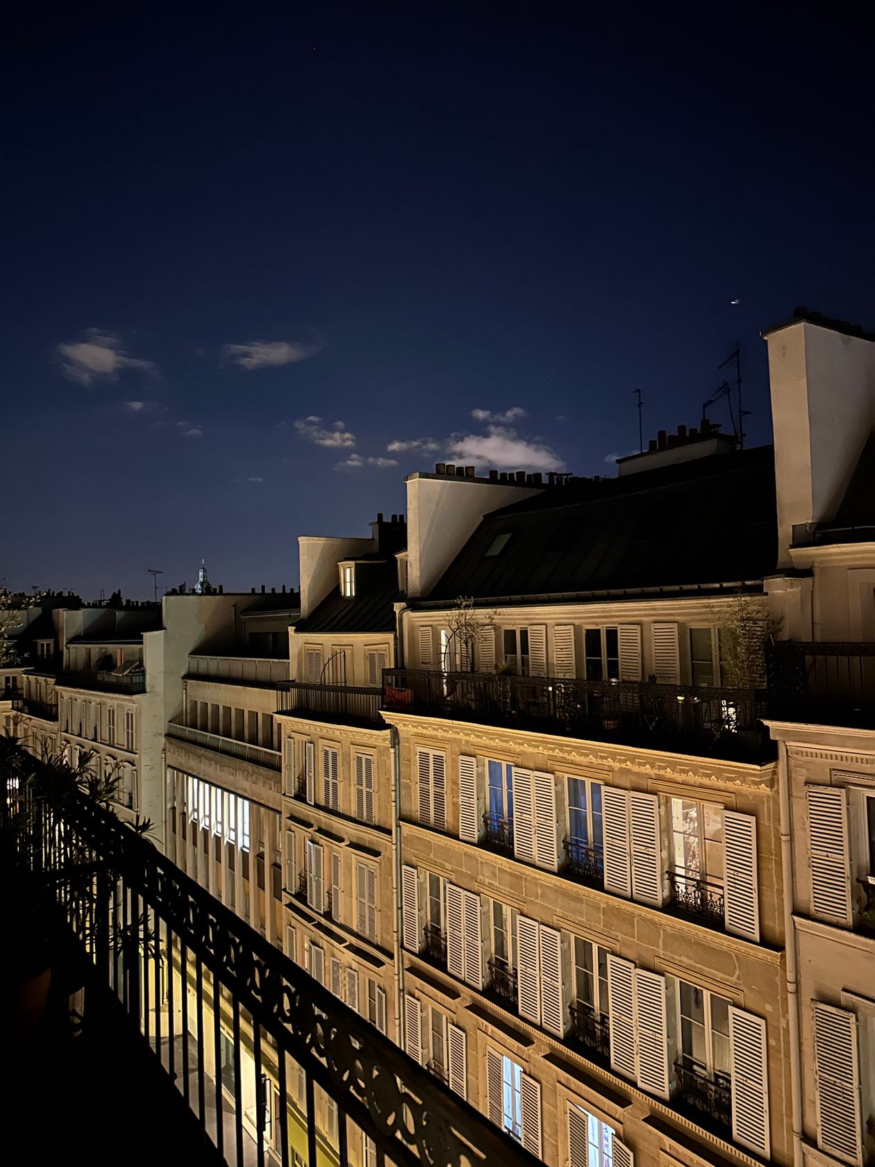 Nighttime view of Parisian rooftops with the Eiffel Tower in the background