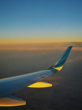 Airplane wing silhouetted against a vibrant sunset sky during a flight.
