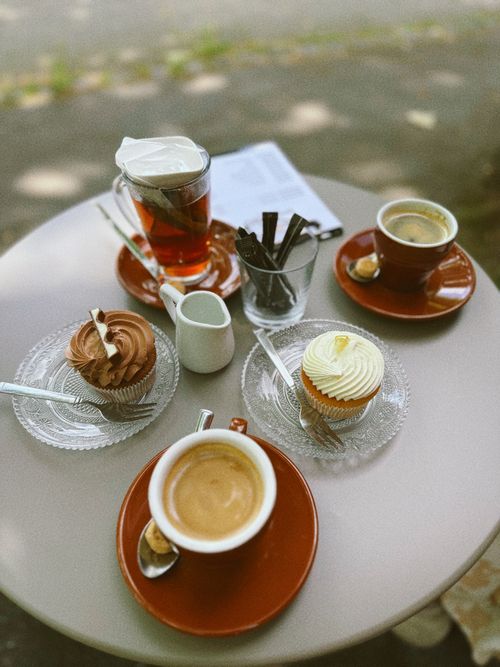 Free Outdoor cafe table with coffee, tea, and cupcakes for a cozy gathering. Stock Photo