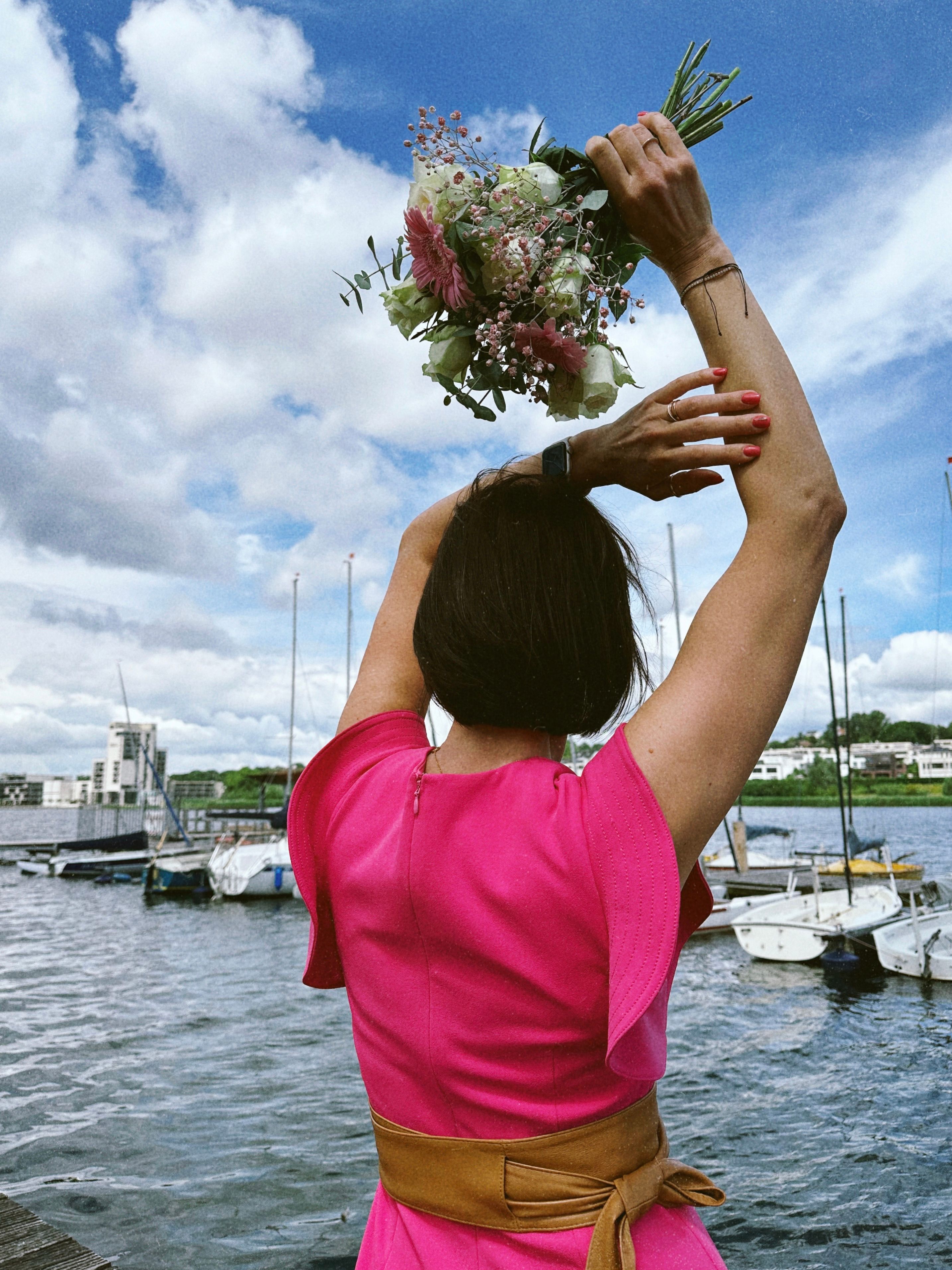 Woman in Pink Dress Holding Flowers by Lake · Free Stock Photo