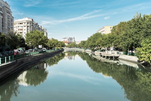 Discover the serene beauty of Dâmbovița River in Bucharest on a sunny day.
