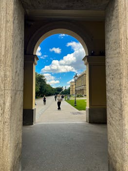 Scenic view through an archway, capturing Munich's vibrant architecture and lush greenery.
