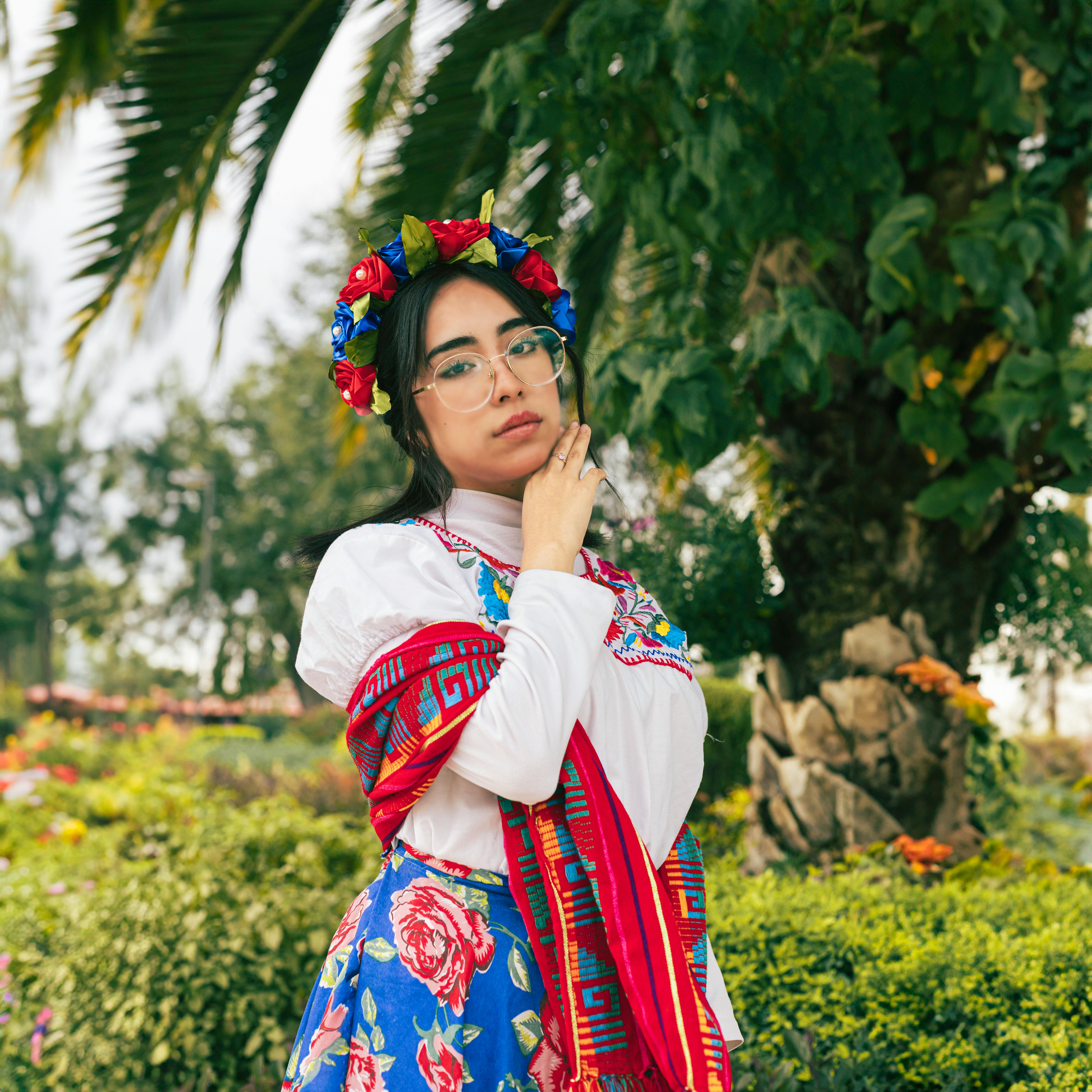 Colorful portrait of a woman in Mexican traditional dress with floral headpiece outdoors.